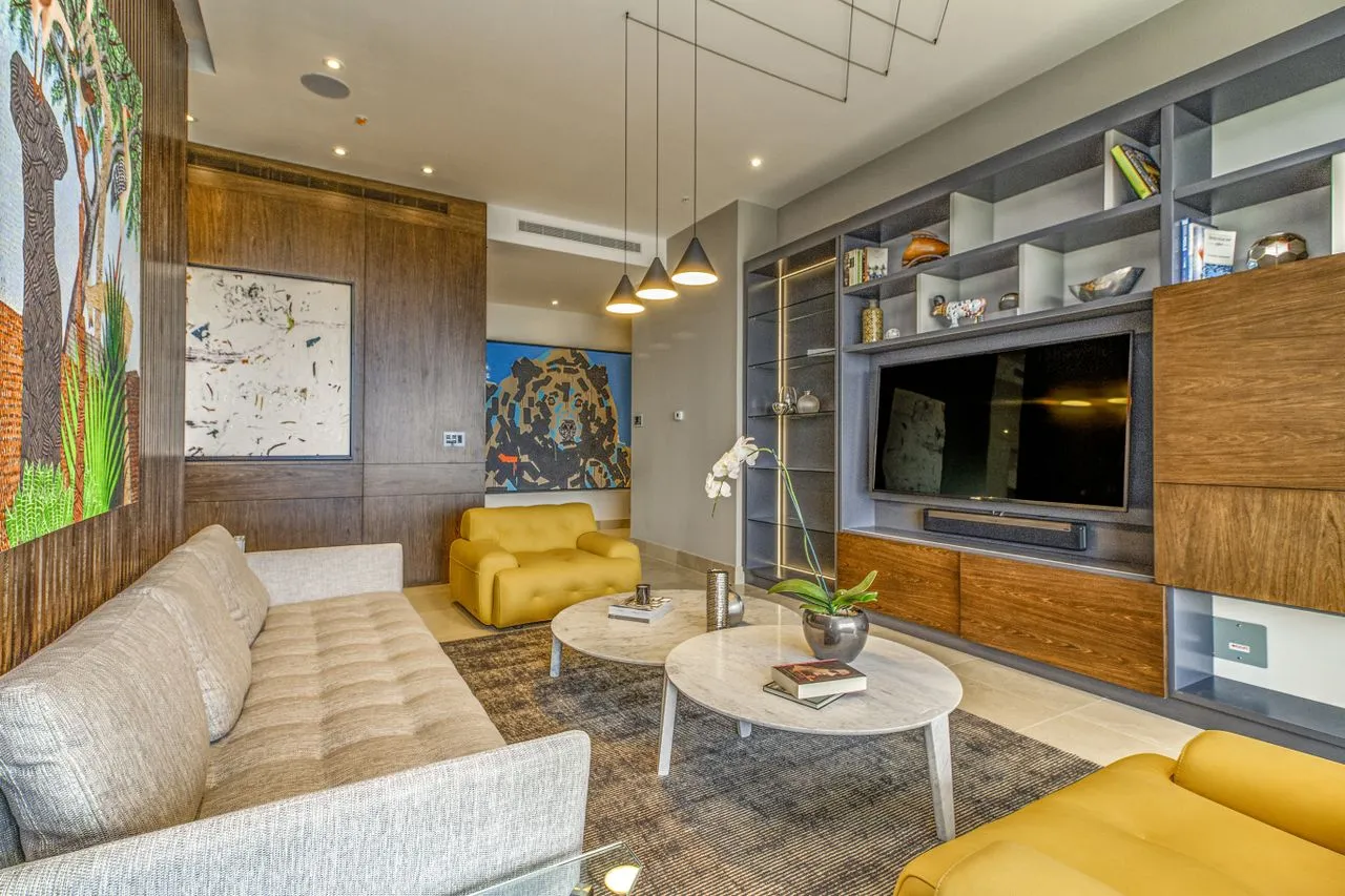 Living room composition with integrated joinery, artwork, lighting and yellow seating