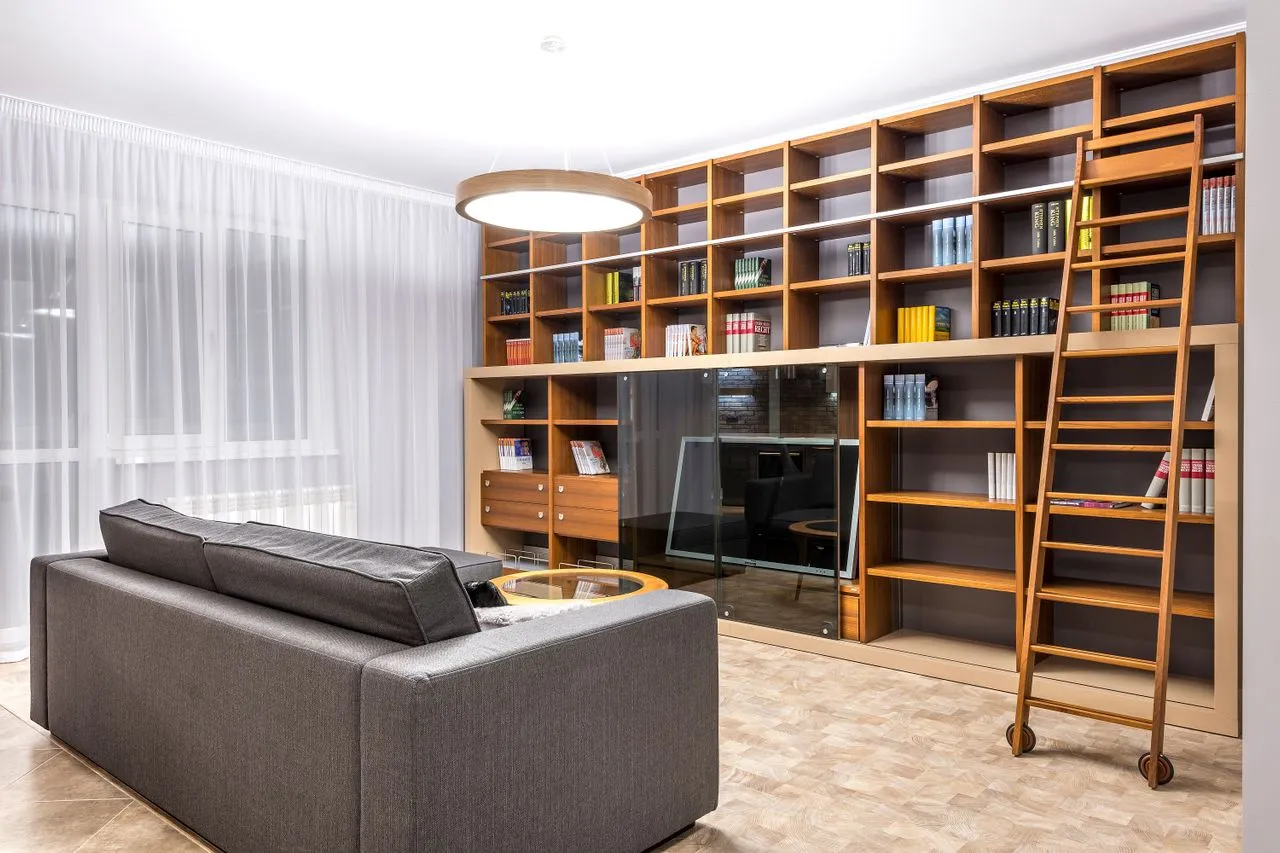 Lived-in library with floor-to-ceiling timber shelving, a rolling ladder and sofa