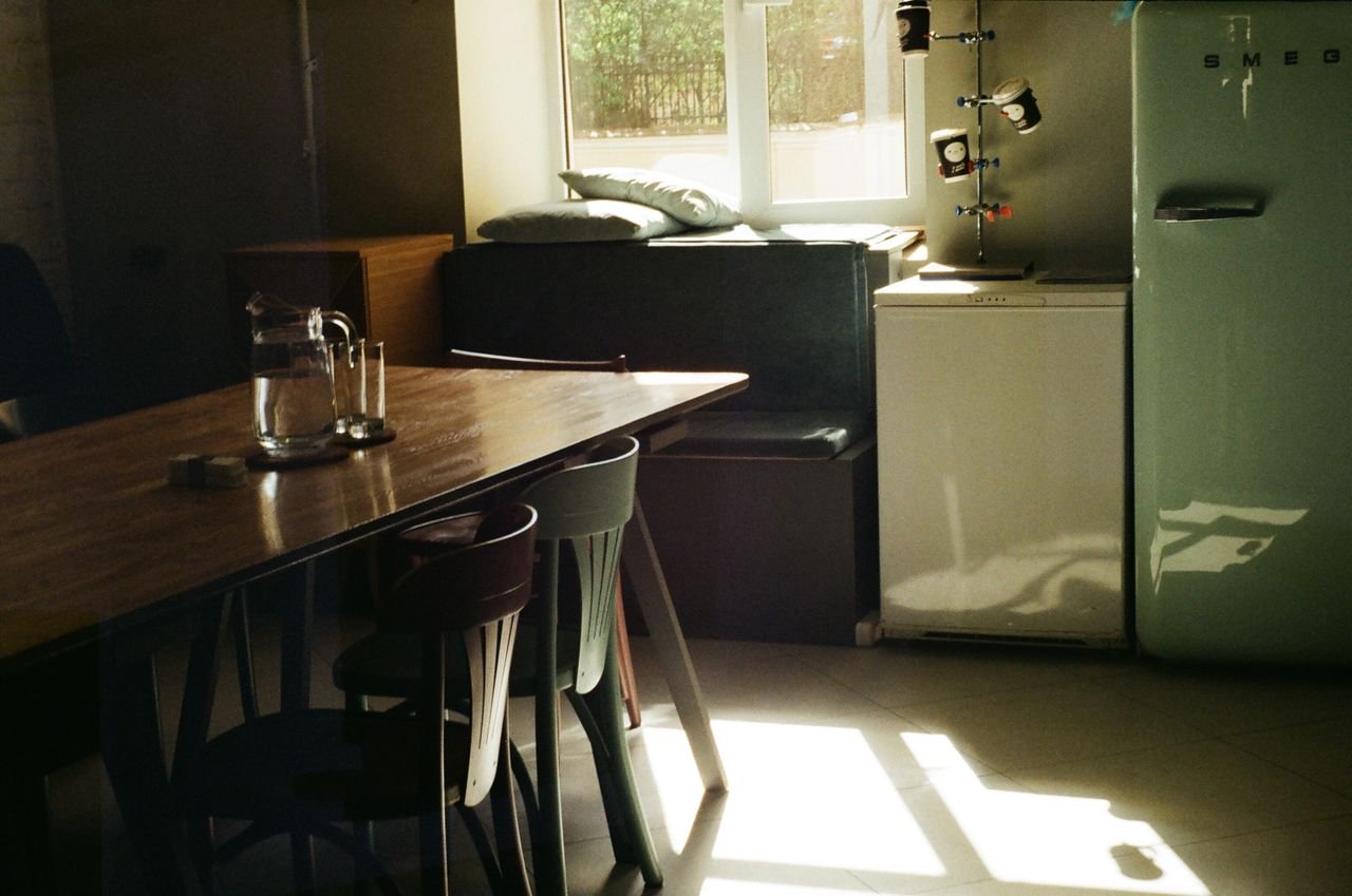 Morning light crossing a kitchen table and green cabinetry