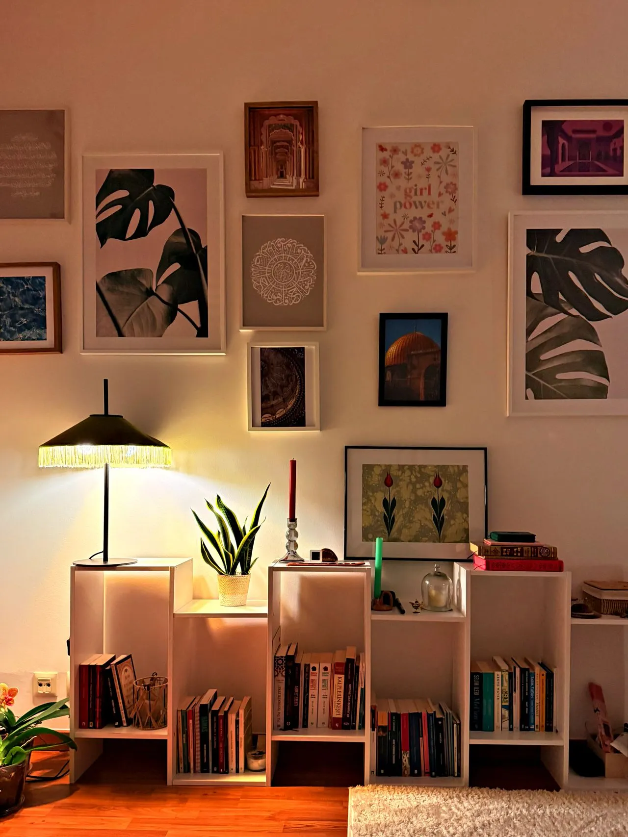 Warmly lit wall displaying a collection of small artworks