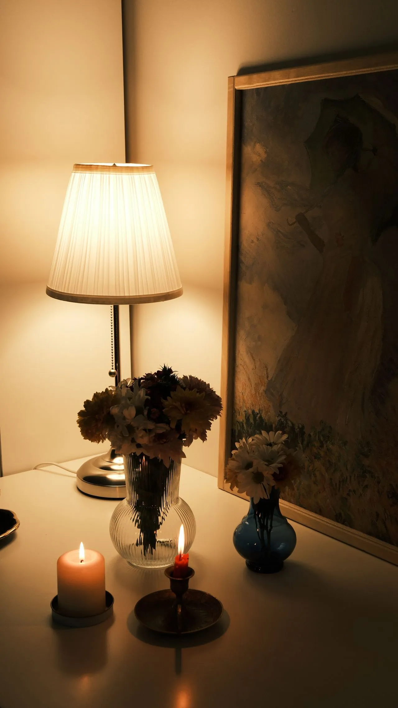 Table lamp illuminating flowers, candles and artwork